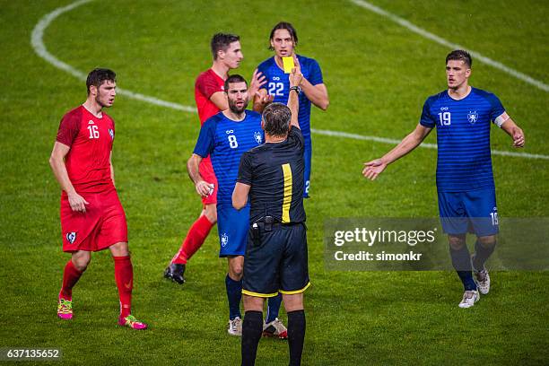 referee holds up yellow card - football player standing stock pictures, royalty-free photos & images