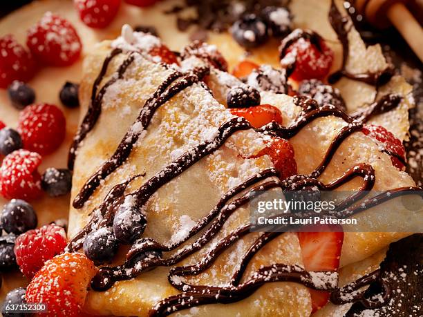 crepes with fresh berries, chocolate sauce and powdered sugar - poedersuiker stockfoto's en -beelden