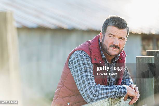 man outside barn leaning on wooden fence - tradesman real people man stock pictures, royalty-free photos & images