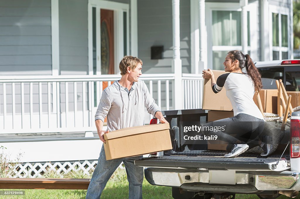 Young couple and pickup truck loaded with boxes and furniture
