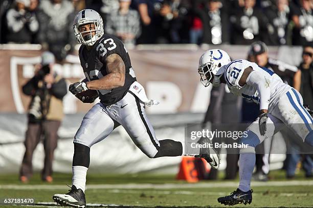 Running back DeAndre Washington of the Oakland Raiders runs for his second 22-yard touchdown against cornerback Vontae Davis of the Indianapolis...