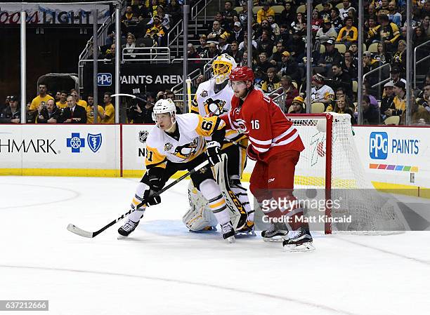 Elias Lindholm of the Carolina Hurricanes and Steven Oleksy of the Pittsburgh Penguins fight for position in front of the net at PPG PAINTS Arena on...