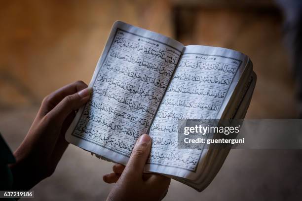 female hands holding a koran book - koran 個照片及圖片檔