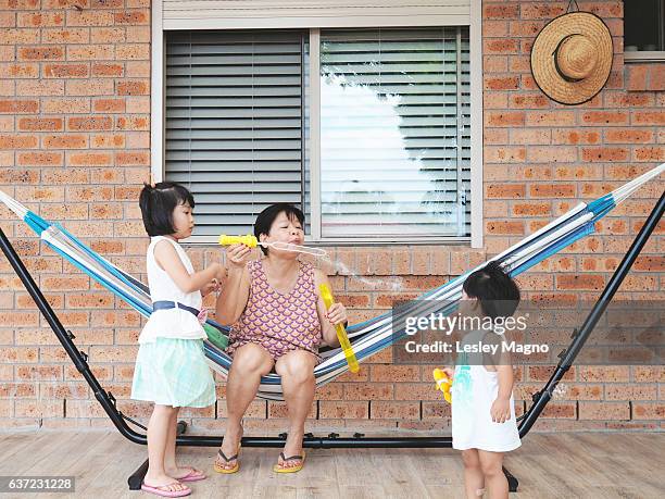 grandma (grandmother) is blowing bubbles for her two grandkids - filipino ethnicity stock pictures, royalty-free photos & images