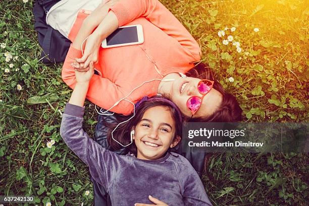 relaxed girls sunbathing in the park - mp3 player stock pictures, royalty-free photos & images