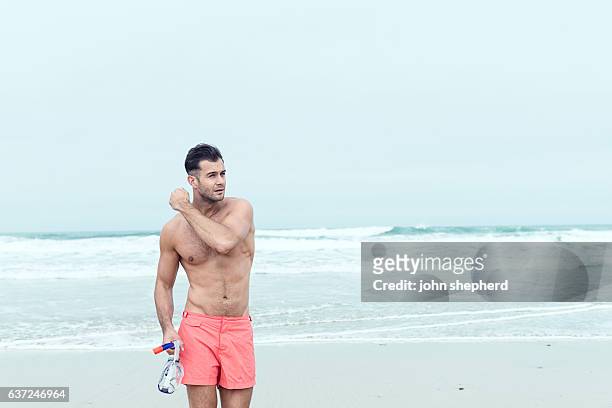 man walking along a beach in swim shorts with snorkel. - bermuda snorkel stock pictures, royalty-free photos & images