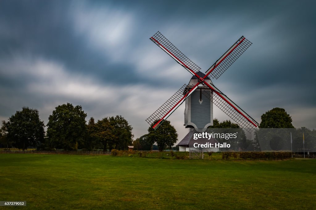 Traditional wind mill in Lomel, Belgium, with clouds and grass field,long exposure.