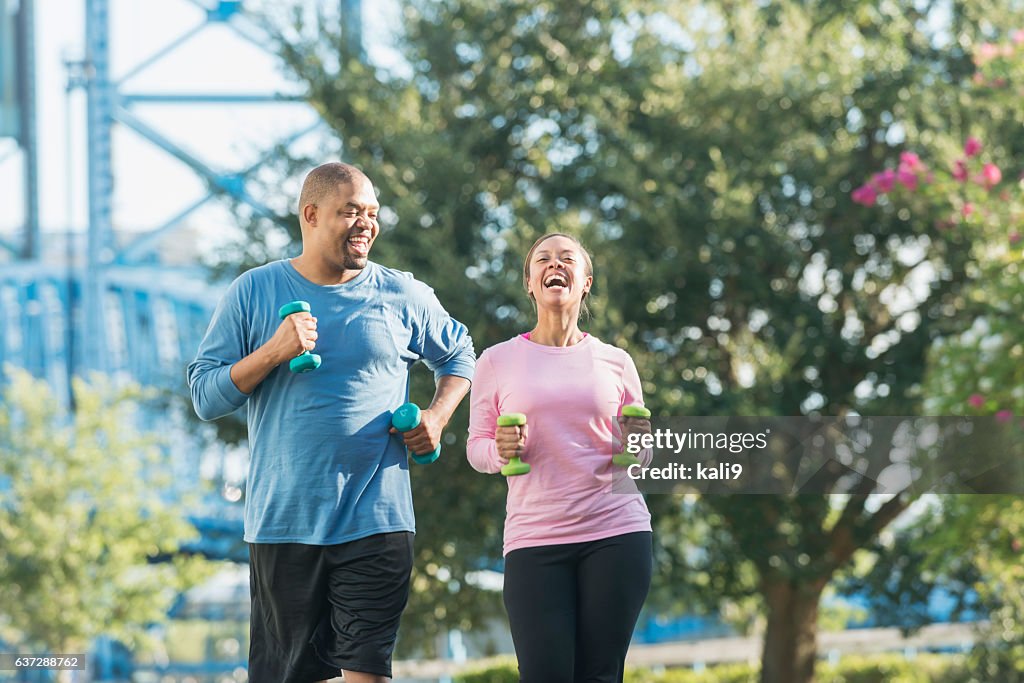 Black couple running together in park, laughing