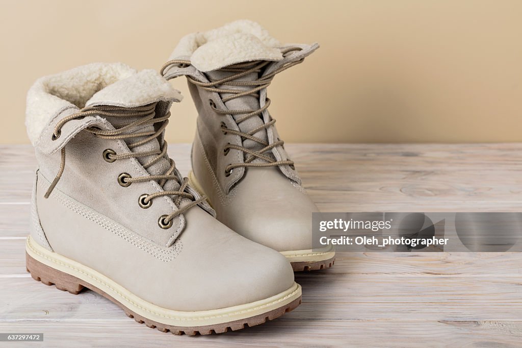 Bright leather winter boots on a light wooden background.