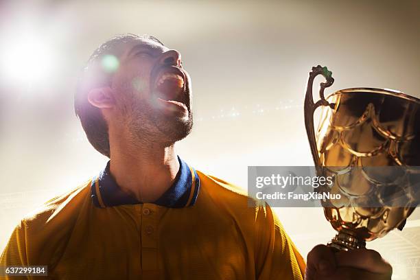 athlete holding trophy cup in stadium - winning cup stock pictures, royalty-free photos & images