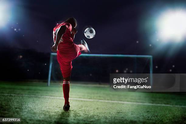 athlete kicking soccer ball into a goal - forward athlete stockfoto's en -beelden