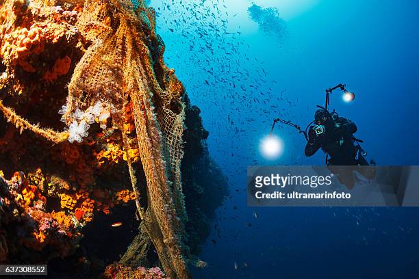 taucher unter wasser fotograf fotografieren erkunden sie das riff alten fischernetz - underwater film camera stock-fotos und bilder