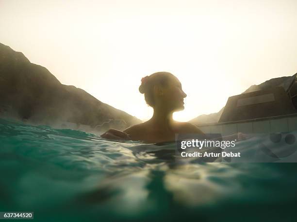 gil swimming and relaxing in a outdoor spa swimming pool during sunset in a relaxed christmas vacations on the catalan pyrenees. - therme stock-fotos und bilder