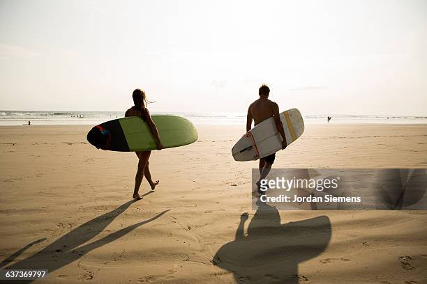 two people walking wit surfboards. - nosara costa rica stock pictures, royalty-free photos & images