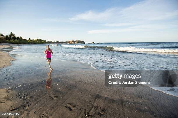 a female jogging on a beach. - nosara costa rica stock pictures, royalty-free photos & images