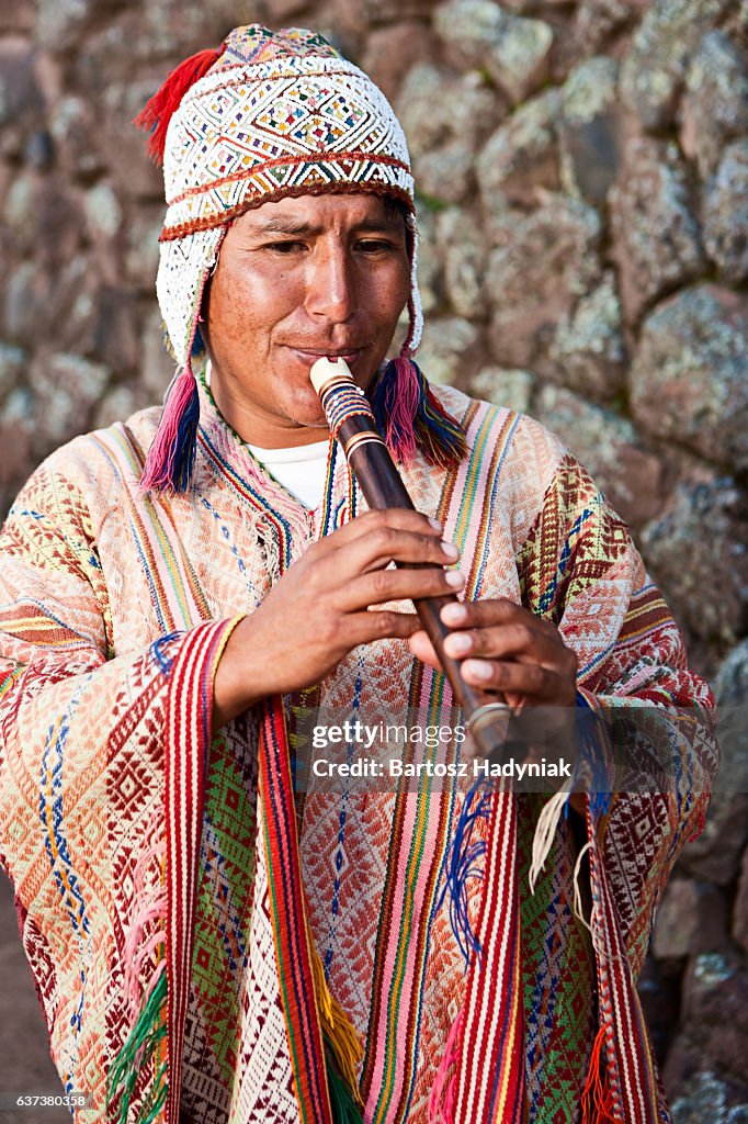 Portrait of Peruvian man playing a flute, Inca ruins, Pisac