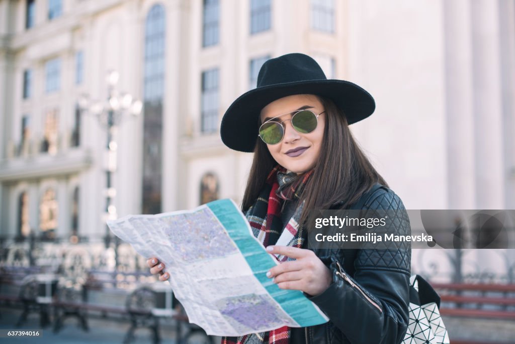 Young woman on the street reading map to find her destination