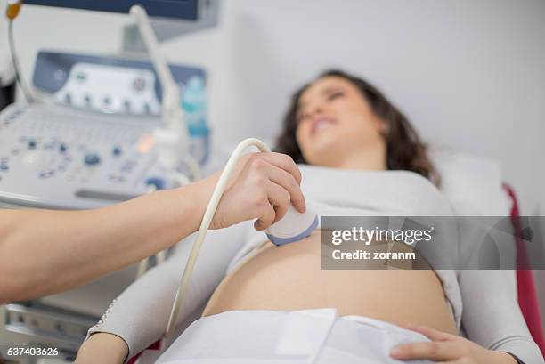 doctor performing ultrasound on pregnant woman - echo stockfoto's en -beelden