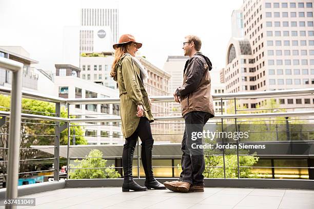 a man and woman smiling in the city. - green coat stock pictures, royalty-free photos & images