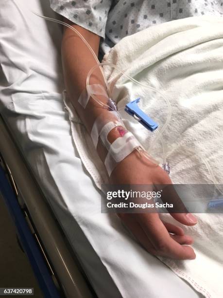 patient in hospital bed with intravenous saline drip tubes in arm - saline drip stock pictures, royalty-free photos & images