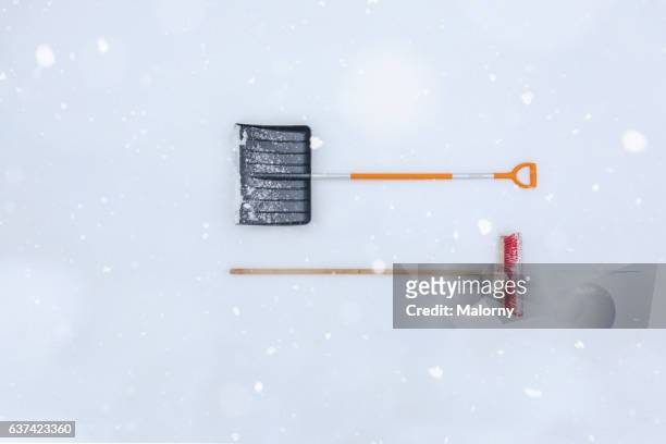 snow shovel and broom in snow, during snowfall. view from directly above. knolling. still life. high angle view. - snow shovel stock-fotos und bilder