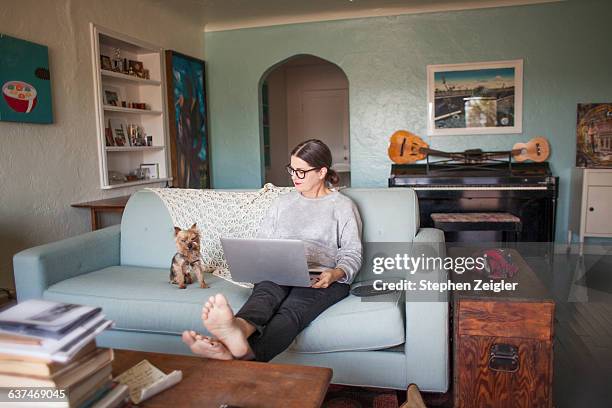 woman sitting on couch with laptop computer - barefoot woman 個照片及圖片檔