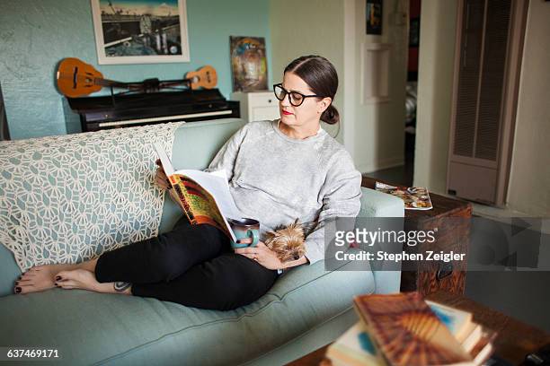 woman on couch reading - reading stock pictures, royalty-free photos & images