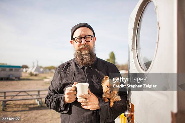 bearded man holding small dog and coffee cup - man tatoo bildbanksfoton och bilder