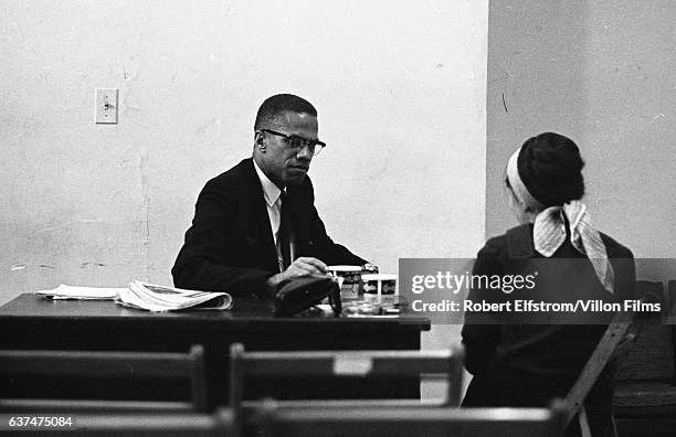 American religious and Civil Rights leader Malcolm X speaks with an unidentified woman at the Lenox Hotel, Boston, Massachusetts, 1964.