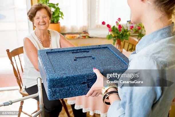 hot meal delivery to an elderly woman at home - meals on wheels stock pictures, royalty-free photos & images