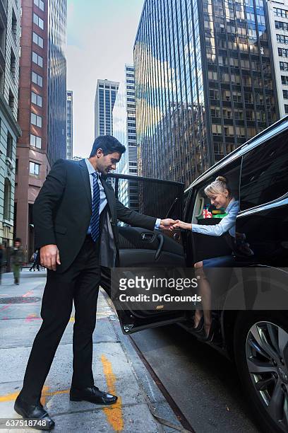 conductor ayudando a passanger fuera de coche de lujo - limousine fotografías e imágenes de stock