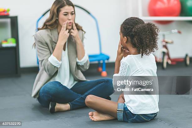 a female speech pathologist is teaching a child patient - speech therapist stock pictures, royalty-free photos & images