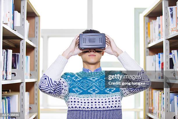 young asian man holds vr in library - university asian students international portrait stock pictures, royalty-free photos & images