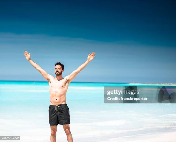 mann allein am strand betet zur sonne - arm sun beach stock-fotos und bilder
