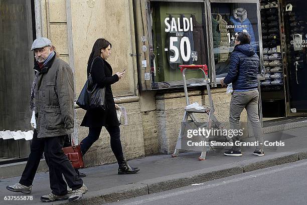 Man prepares a shop window that indicates "sales" in Via del Corso on January 4, 2016 in Rome, Italy. The winter sales begin in Rome tomorrow on...