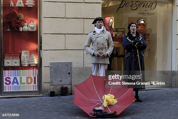 Two street artists in costumes singing in front of a shop window that indicates "sales" in Via Frattina on January 4, 2017 in Rome, Italy. The winter...