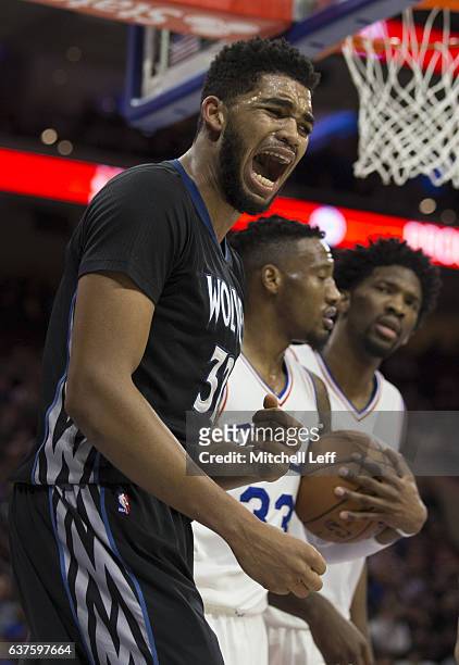 Karl-Anthony Towns of the Minnesota Timberwolves reacts in front of Robert Covington and Joel Embiid of the Philadelphia 76ers in the third quarter...