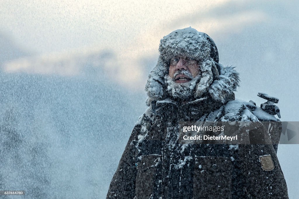 Man with furry  in snowstorm with cloudy skies and snowflakes
