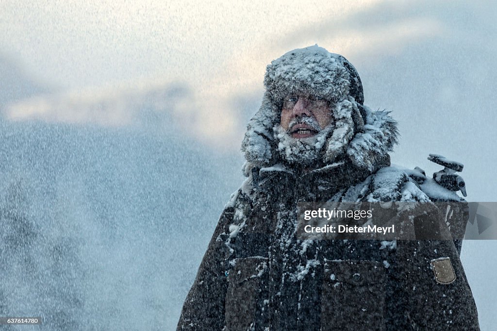 Homem peludo em tempestade de neve com céu nublado e flocos de neve