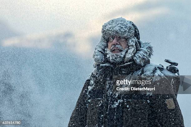 man with furry  in snowstorm with cloudy skies and snowflakes - rock climber bildbanksfoton och bilder