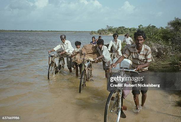 Local Tamil residents push bicycles to a fiber glass motorboat to cross a lagoon October 1, 1998 to and from Batticaloa and Jaffna in...