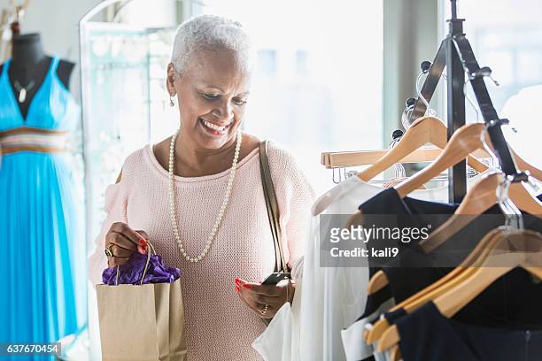 mature black woman shopping in a clothing store - boutique stock pictures, royalty-free photos & images