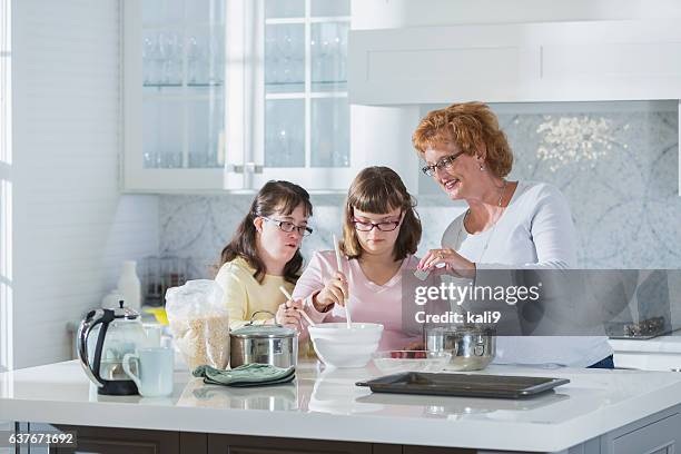 mother and two daughters with down syndrome, baking - down syndrome cooking stock pictures, royalty-free photos & images