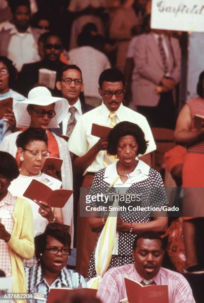 Members of the Jehovah's Witnesses singing in an annual worship convention at Sox Park, a baseball field on the South Side of Chicago, Illinois,...