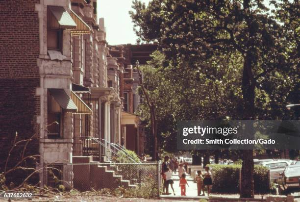 Young boys and girls stroll together under the trees that line a West Side neighborhood in Chicago, Illinois, 1973. Image courtesy National Archives....