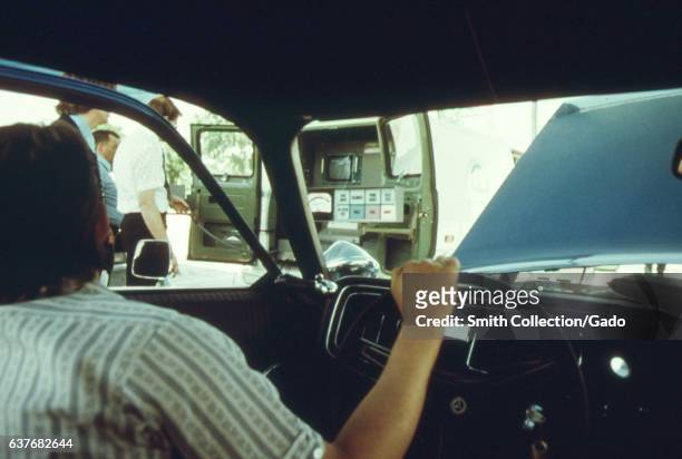 Motorist grips the steering wheel while looking out at an auto pollution test site at Soldier's Field, Chicago, Illinois, 1973. Image courtesy...