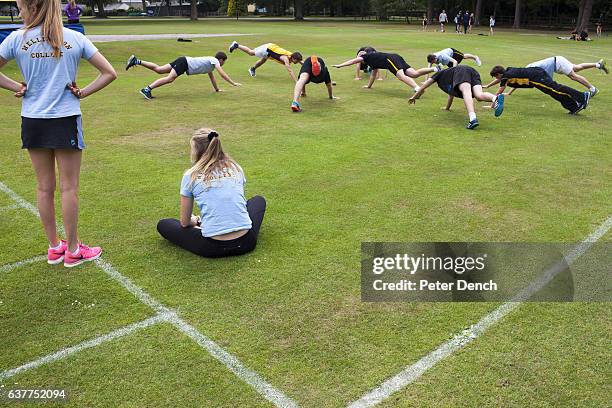 Two girls watch on as boys are put through physical training during games at Wellington College. Wellington College is a British co-educational...