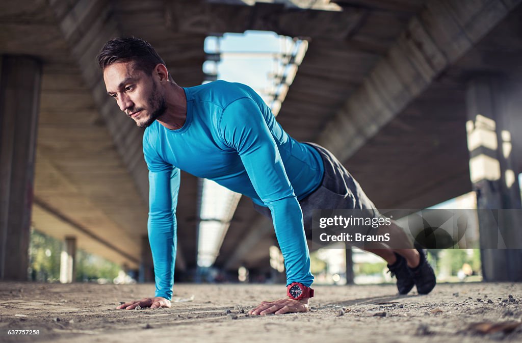 Jeune homme athlétique en position de planche dans la rue.