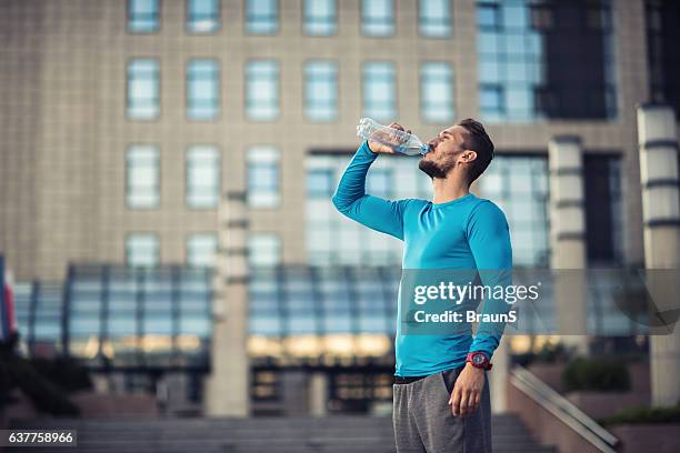 athletic man drinking fresh water on the city street. - man drinking water stock pictures, royalty-free photos & images