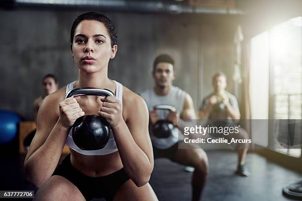 burning calories and strengthening her core with a kettlebell - women working out gym stock pictures, royalty-free photos & images
